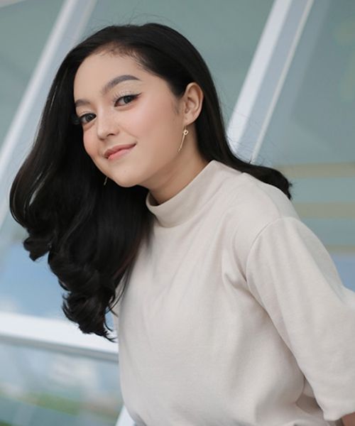 Woman with long hair smiling in casual attire.